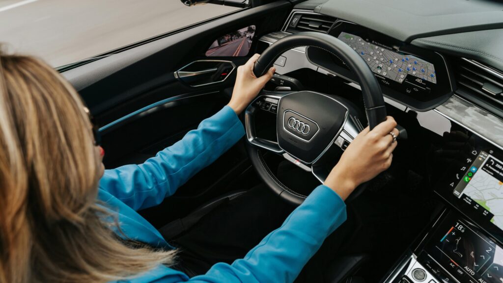 High angle view of a woman driving a modern Audi car, showcasing the dashboard and steering wheel.