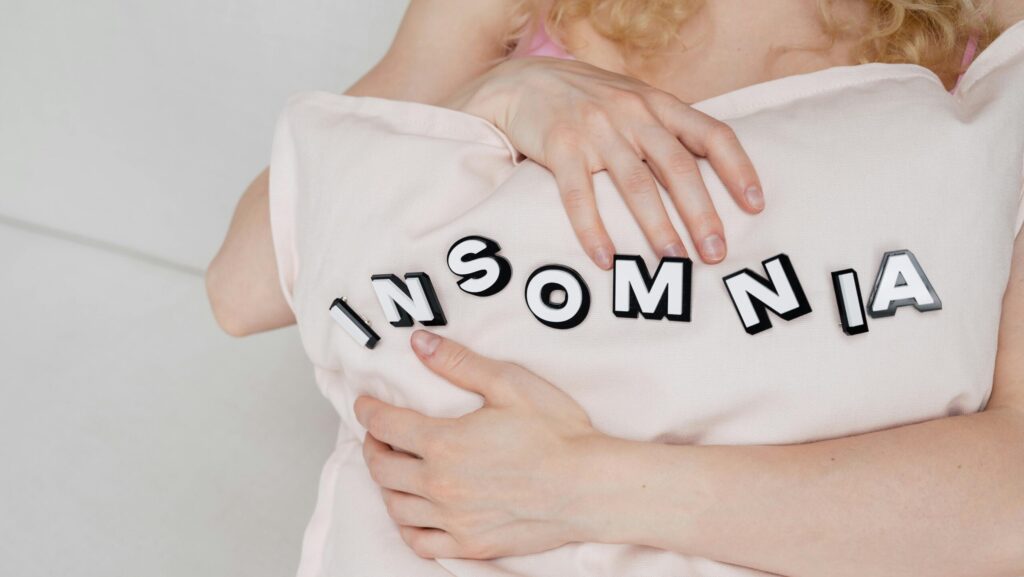 Close-up of a woman holding a pillow with 'insomnia' text, depicting sleep disorder.